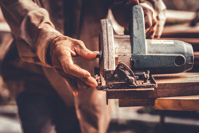 Midsection of man working on metal machine