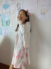 Portrait of cute girl standing against wall