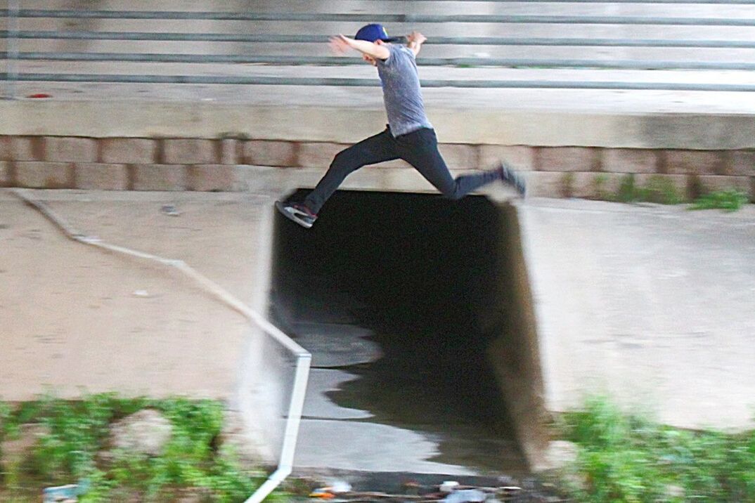 LOW SECTION OF MAN JUMPING ON MOBILE PHONE OUTDOORS