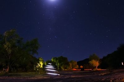 Road amidst trees against sky at night