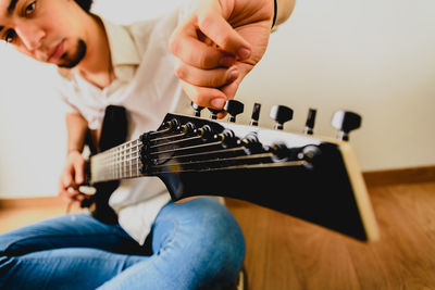 Midsection of man playing guitar at home