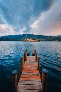 Wooden jetty on pier over lake against sky