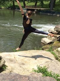 Full length rear view of ballerina dancing by lake in park