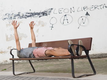 Man with arms raised lying on bench