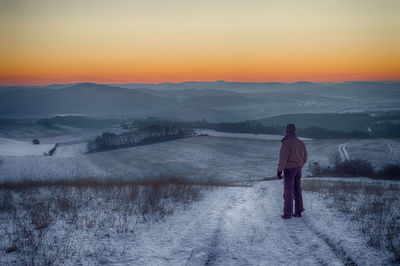 Rear view of man standing on snow covered landscape