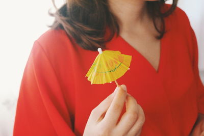 Midsection of woman holding yellow drink umbrella