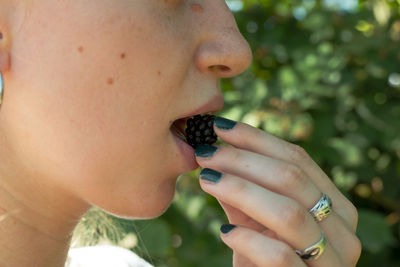 Midsection of woman eating blackberry 