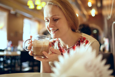 Beautiful happy woman having cappuccino in cafe