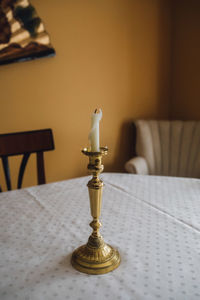 Elegant golden brass taper candlestick on dining table with golden walls