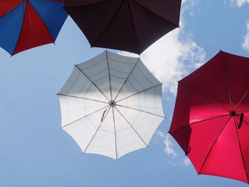 Directly below shot of umbrellas hanging against blue sky