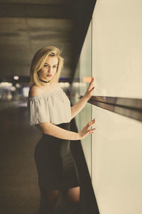 Portrait of young woman standing by window