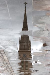 View of built structure reflected in puddle