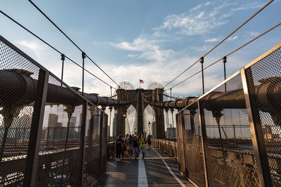 People walking on bridge in city against sky