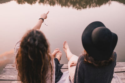 Rear view of female friends sitting on pier