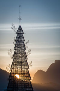 Silhouette of artificial christmas tree against sky at sunset