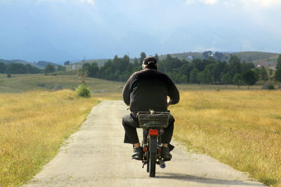 Rear view of man riding bicycle on road