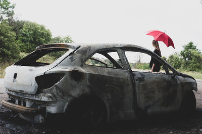 Abandoned car on field against sky