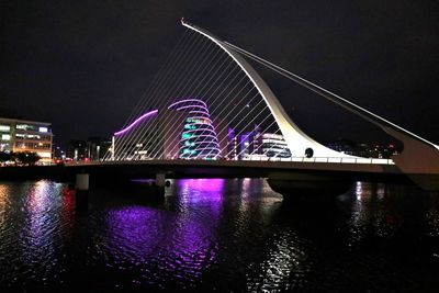 Illuminated bridge over river at night