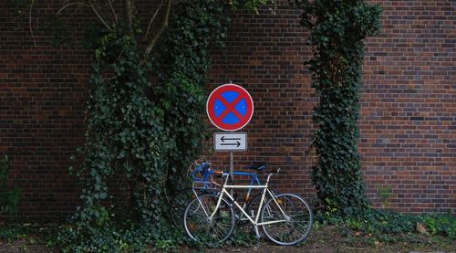 Bicycle sign against brick wall in city