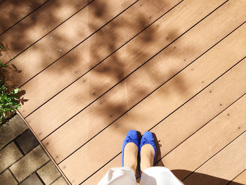 Low section of woman standing on wooden floor outdoors