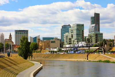 Buildings by river against sky in city