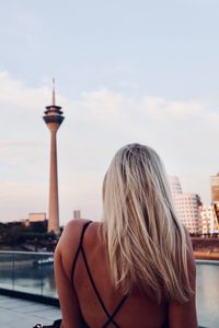 Rear view of woman looking at tower against sky