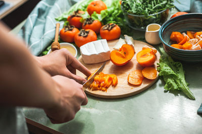 Ingredients and process of making a vitamin winter salad with persimmons, tangerines and cheese