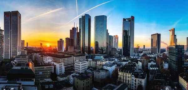 Modern buildings in city against sky during sunset