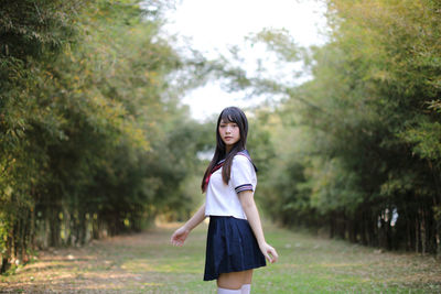 Portrait of young woman standing against trees