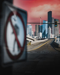 Road by buildings against sky in city