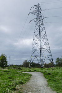 Low angle view of electricity pylon on field against sky