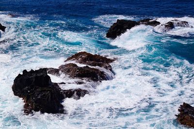 High angle view of waves splashing and crashing  on and over rocks white water surf 