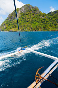 Scenic view of sea by mountain against sky