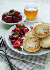 Cottage cheese pancakes, ricotta fritters on ceramic plate with fresh strawberry. 