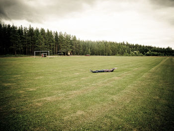 A person lying on a soccer flied in the woods