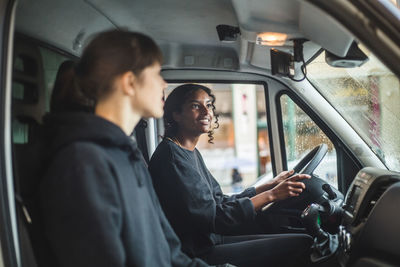 Female mover looking in rear-view mirror while driving truck