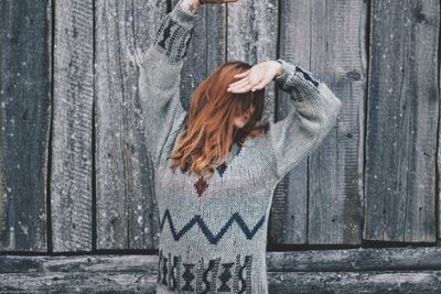 Woman in warm clothing standing against wall