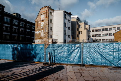 Fence by incomplete buildings at construction site in city