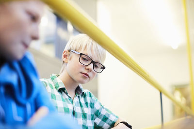 Boy sitting by friend on staircase in middle school