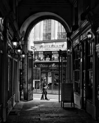 Rear view of woman walking on street amidst buildings in city