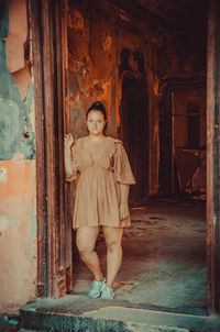 Portrait of woman standing by old building