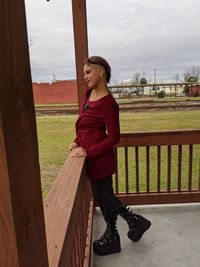 Young woman looking away while standing on railing