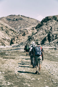 Full length of friends walking on mountain against sky