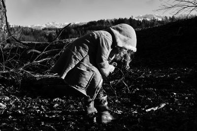 Full length side view of girl wearing warm clothing while bending on land