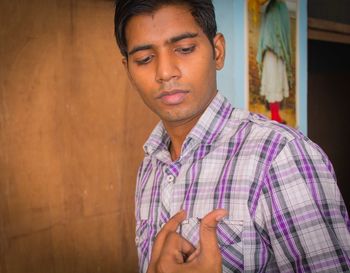 Young man looking at thumb against wall