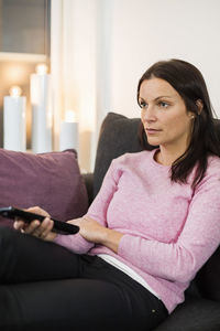 Mid adult woman watching tv on sofa at home
