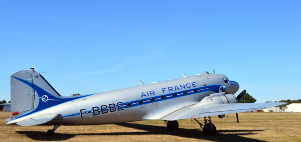 Airplane on airport runway against clear blue sky