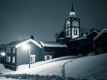 Snow covered buildings against sky at night