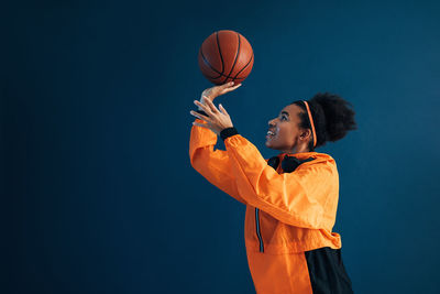 Rear view of man holding basketball hoop against blue background