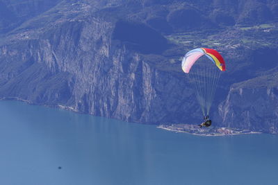 People paragliding over sea against mountains